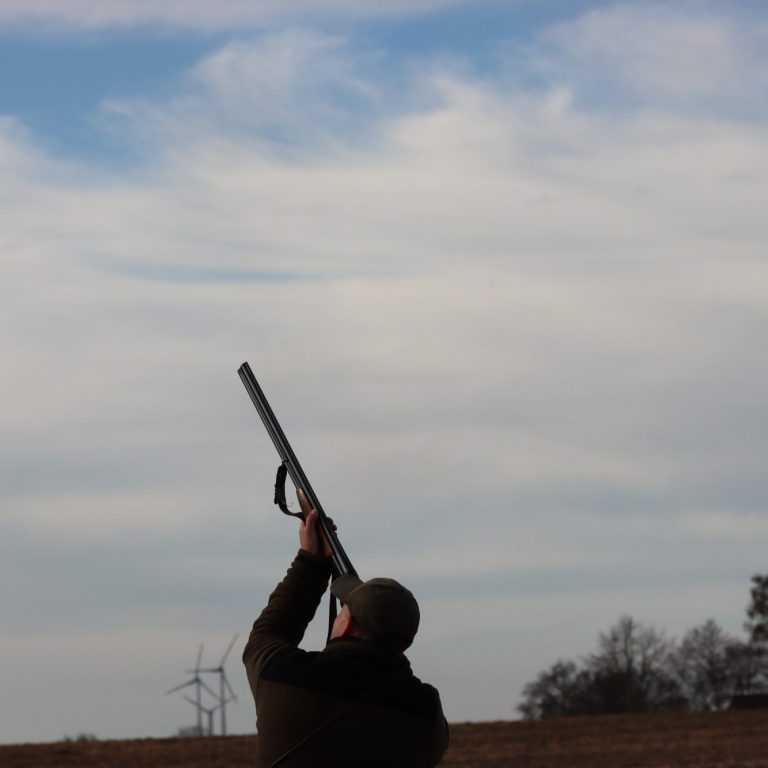 Person mit Gewehr, der in den Himmel schaut, um einen Schuss abzugeben.
